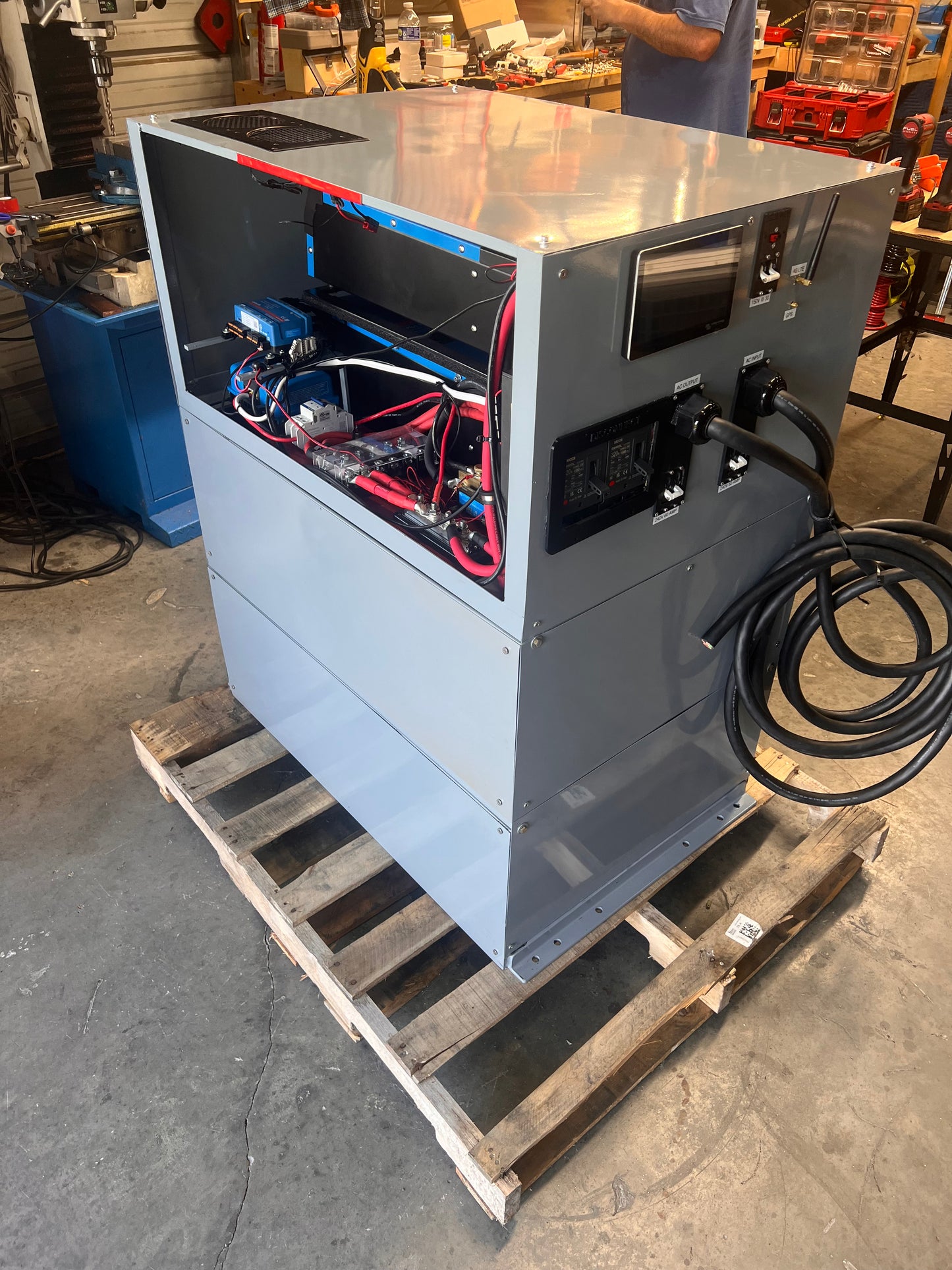 Open computer case on a pallet with visible internal components in a workshop setting