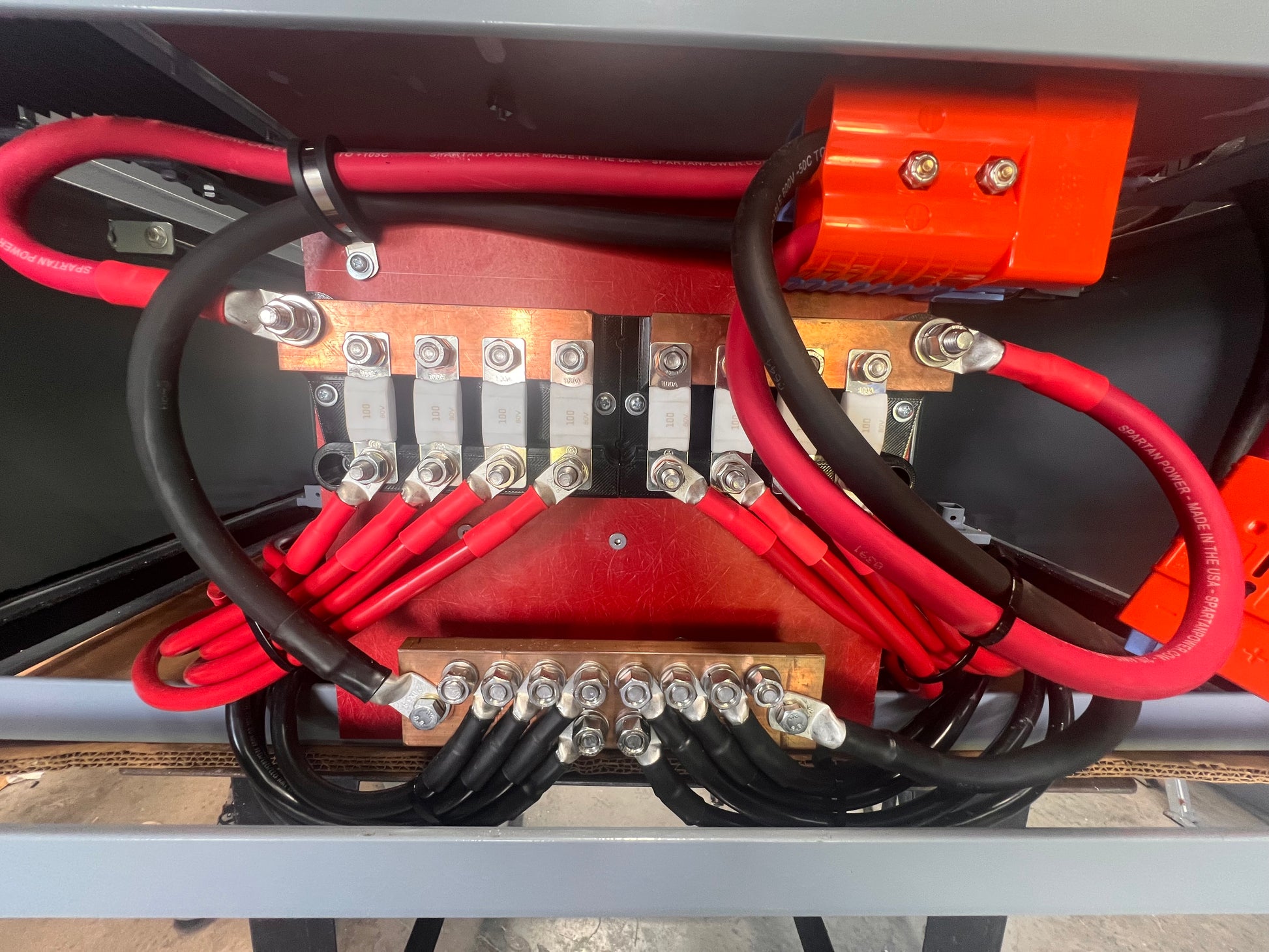 Close-up of electrical wiring with red and black cables on a metallic surface.
